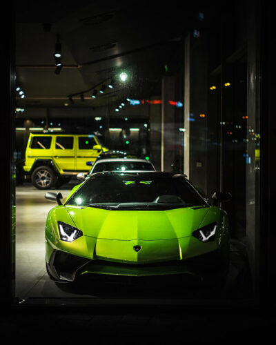 Green Lamborghini Aventador in a dealership window.
