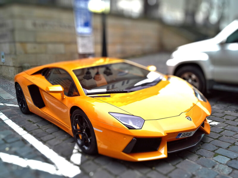 Yellow-organge Lamborghini parked in a europeal parking lot.