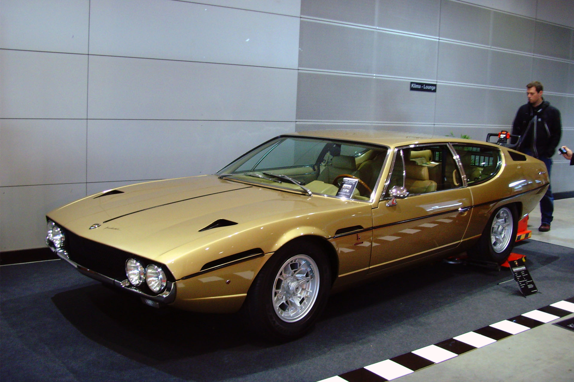 Lamborghini-Espada in gold at an indoor car show.