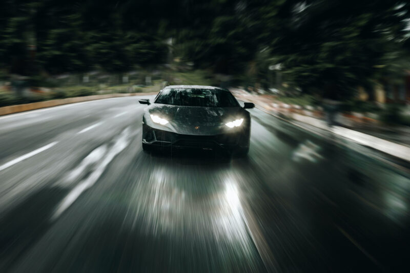 Grey Lamborghini Huracan driving down a snowy road at night.