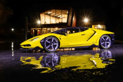Yellow Lamborghini Centenario on display in front of a mansion at night in front of a fountain pool.