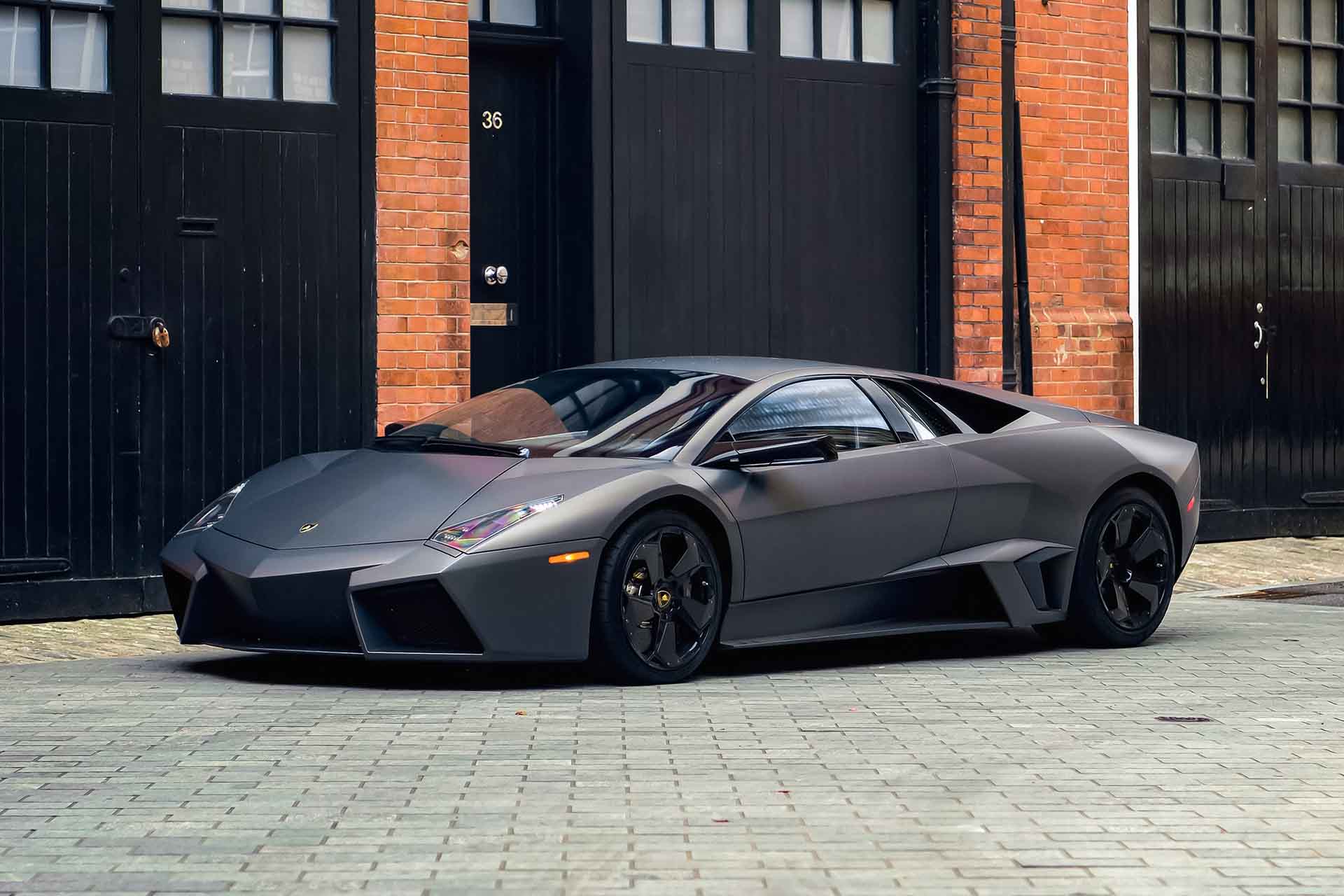 Grey Lamborghini Reventon parked outside a brick industrial building in London, UK.