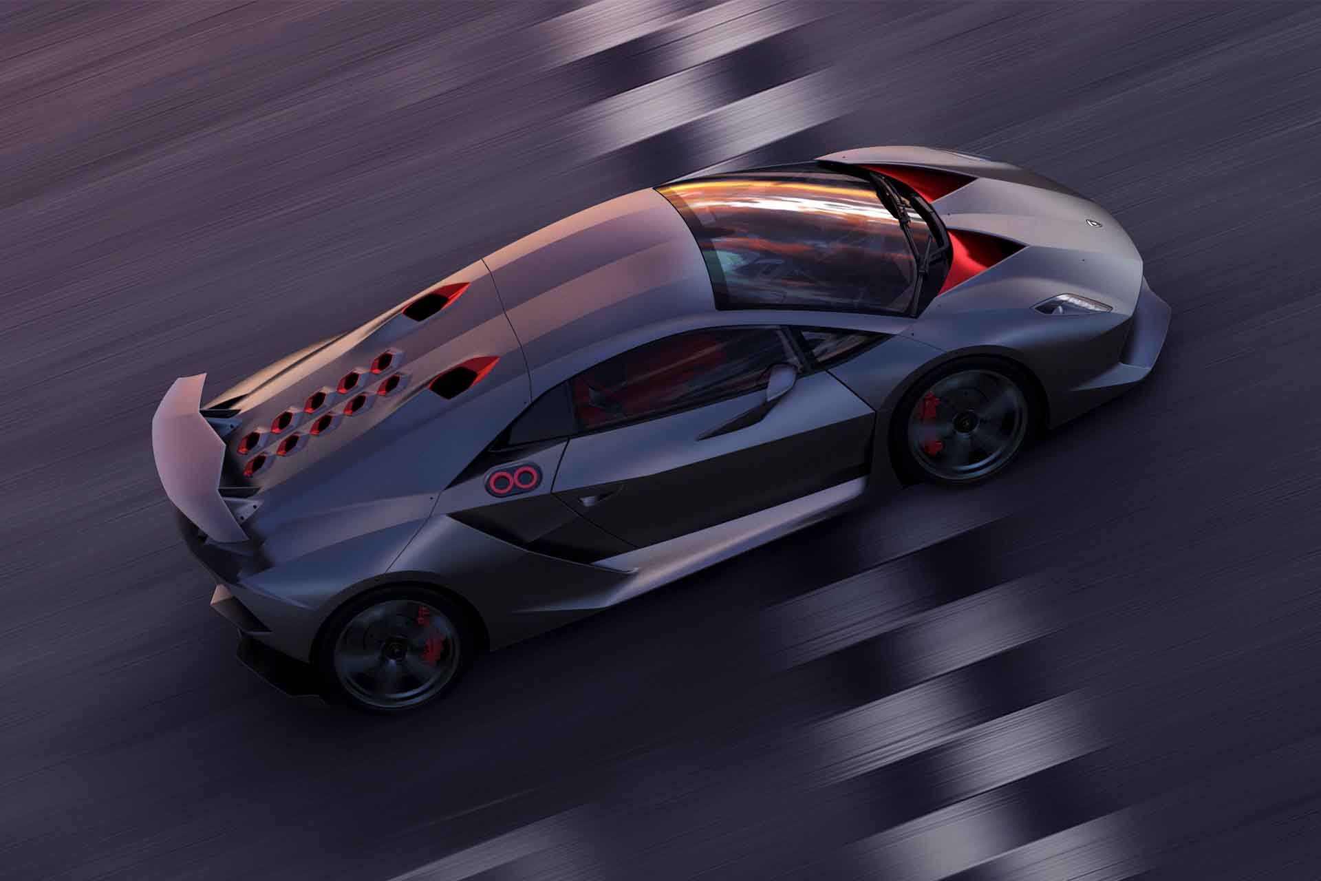 Grey with red accents Sesto Elemento speeding across the finish line of a racetrack at sunset.