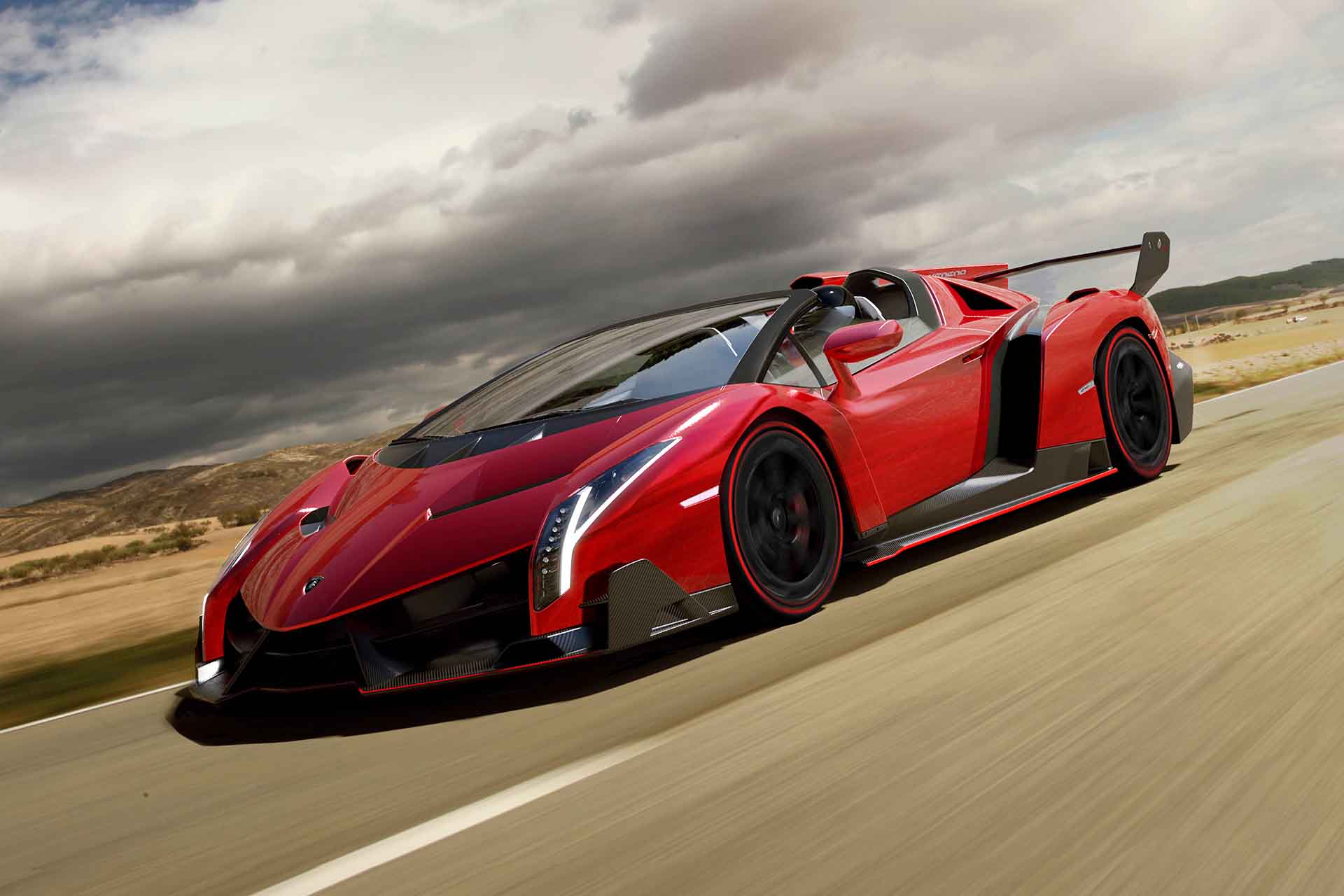 Red Lamborghini Veneno driving fast on a desert road with the top open.
