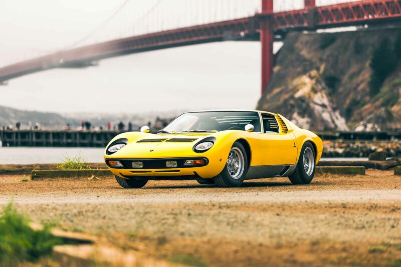 Yellow Lamborghini parked on a dirt parking lot in front of the golden gate bridge in San Francisco.