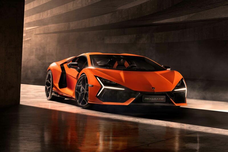 Orange Lamborghini Revuelto supercar front three quarters view entering a concrete garage.