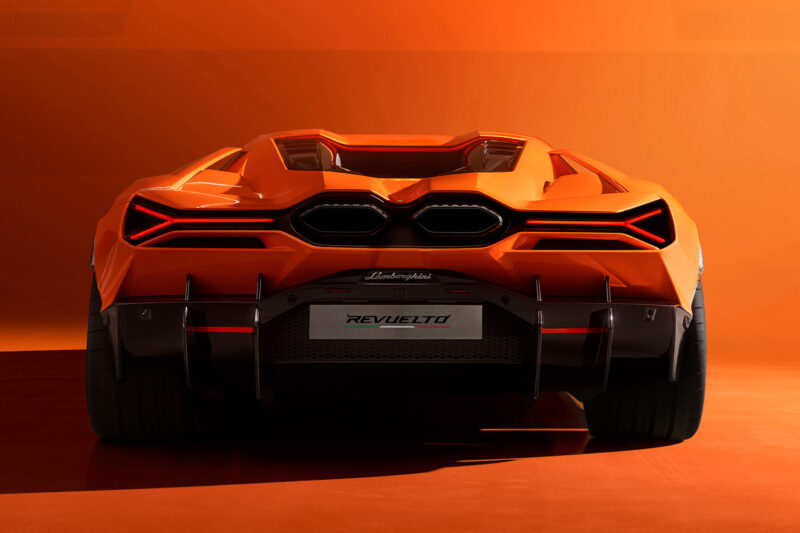 Orange Lamborghini Revuelto supercar in an orange photo studio. Rear view of the tail lights, license plate, large rear tires and exhaust pipes.