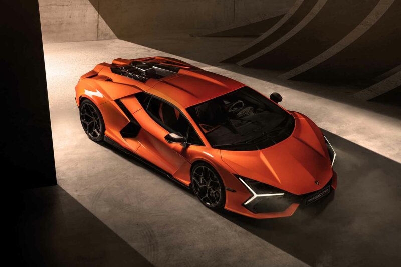 Orange Lamborghini Revuelto supercar. Top view rolling into a concrete garage.