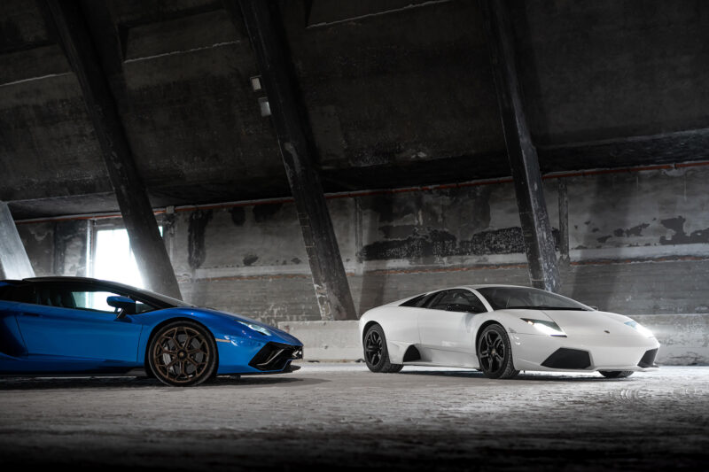 Blue Lamborghini Aventador and white Lamborghini Murciélago in a building.