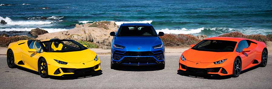 Yellow Huracán, blue Urus and Orange Huracán parked beside the ocean.