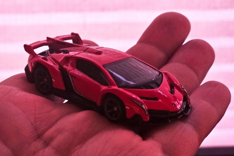 Lamborghini Veneno Hot Wheels car in a hand at sunset.