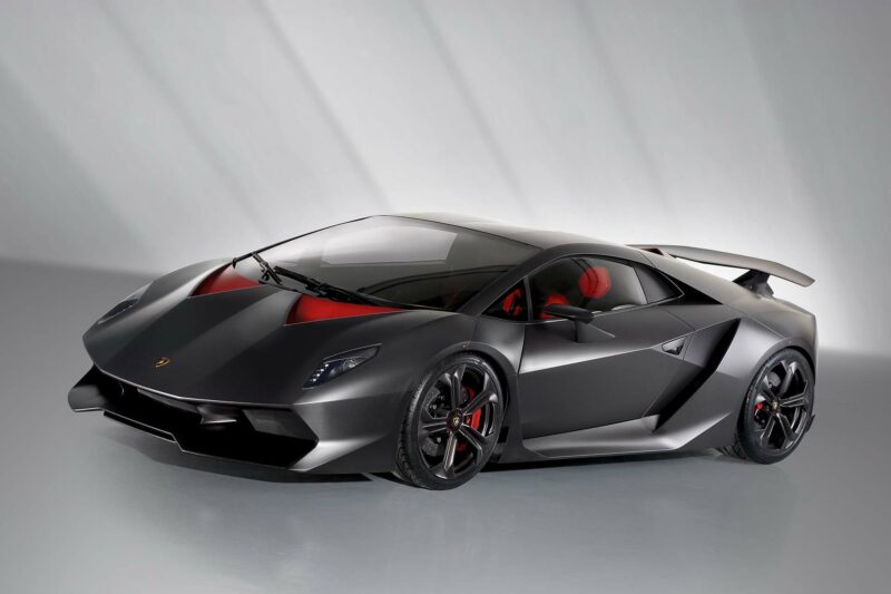 Lamborghini Sesto Elemento in exposed carbon with red accents in a photo studio. Front and side view on a slight angle.