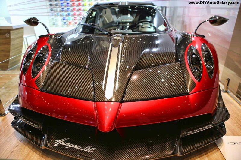 Pagani Huayra in red and exposed carbon fiber in a showroom environment.