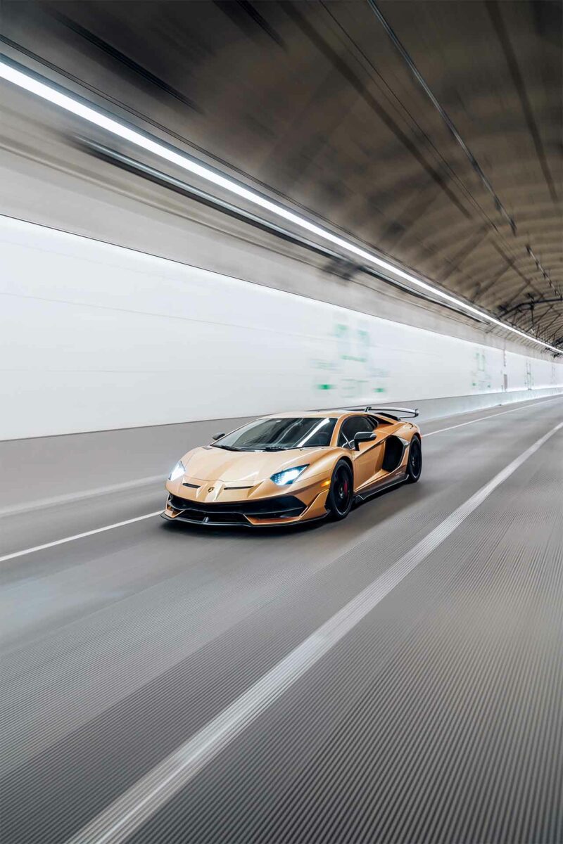 Gold Lamborghini Aventador speeding down a tunnel.