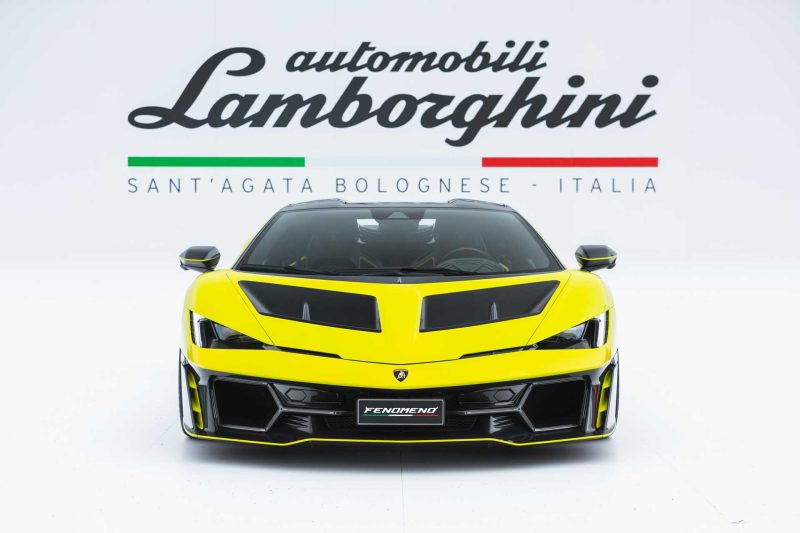 Photo of yellow Lamborghini Femoneno from the front with Lamborghini logo in the background