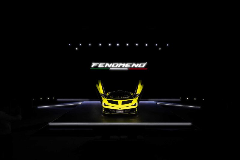 Photo of yellow Lamborghini Femoneno on a stage with the doors open and pointing up. Photo showing the face.